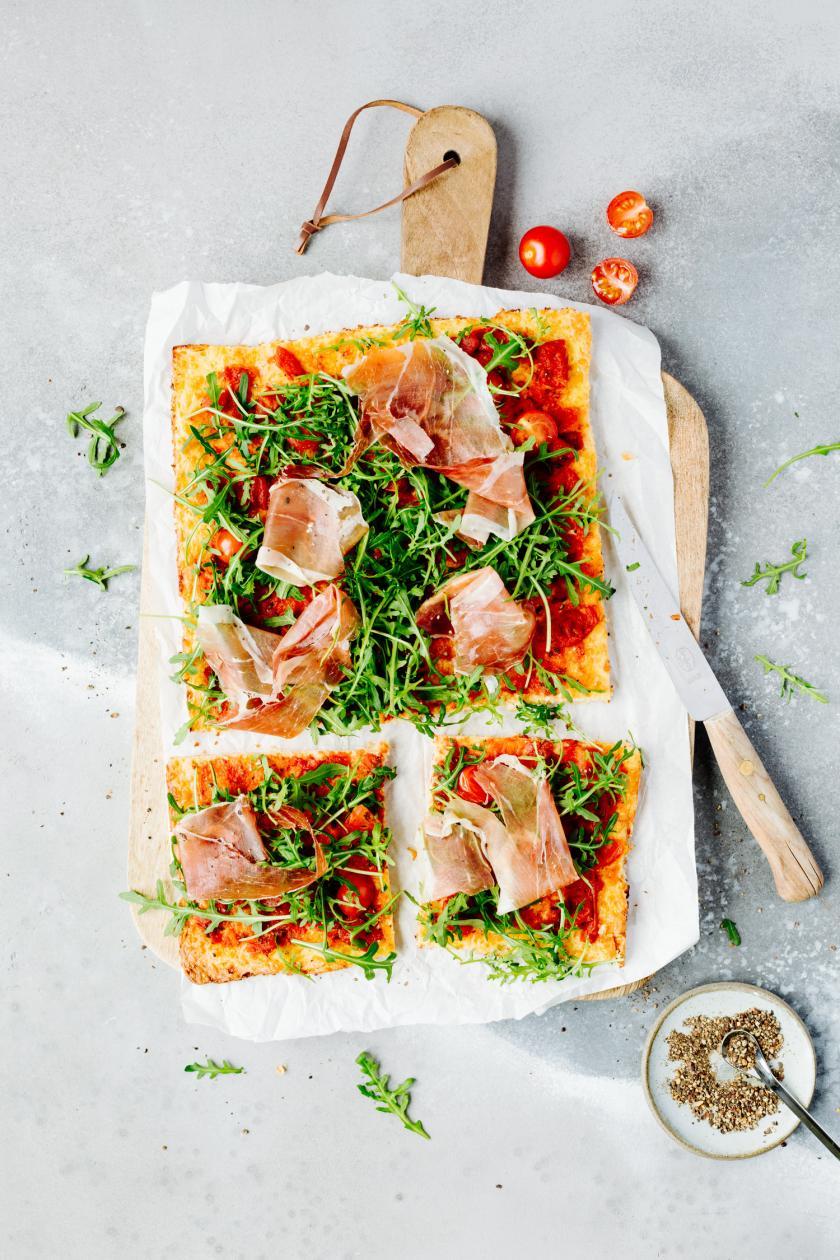 Low Carb Pizza angeschnitten auf einem Holzbrett