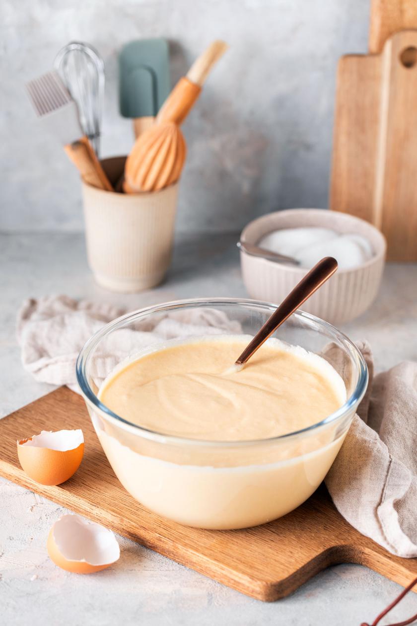 Fertiger Waffelteig nach bestem Rezept in einer Schüssel mit Löffel auf einem Holzbrett.
