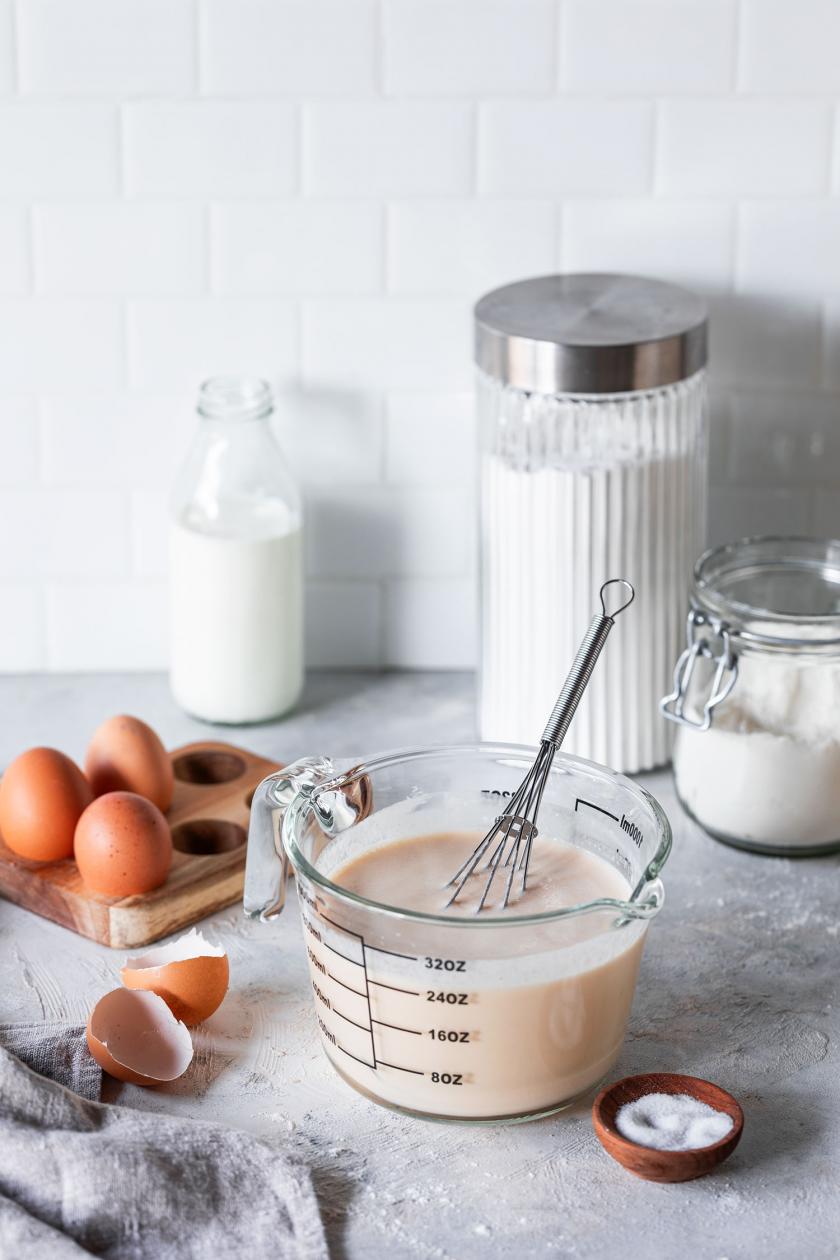 Pfannkuchenteig in einer Glasschüssel, daneben einige Zutaten