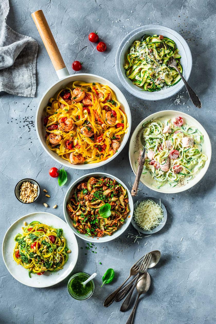 Mehrere Zoodles Gerichte zubereitet und in Tellern auf einem gedeckten Tisch.